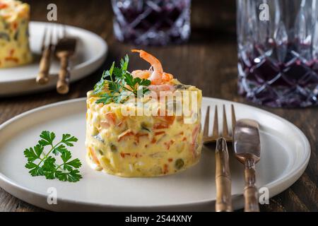 Salade traditionnelle ukrainienne maison saine olivier prête à manger dans une assiette, gros plan. Délicieuse salade de pommes de terre, carottes, petits pois, œufs durs et shri Banque D'Images