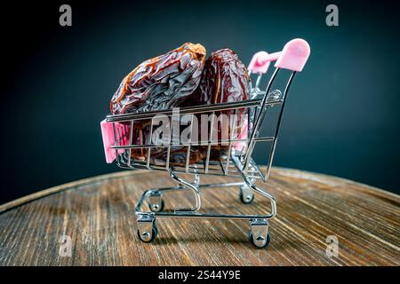 Panier sur roues avec des fruits de dattes sur fond sombre, gros plan. Ce fruit est très nutritif et est couramment consommé pendant le jeûne ou le ramadan Banque D'Images