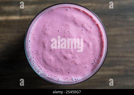 Smoothie à la banane framboise en verre sur une table en bois, gros plan, vue de dessus Banque D'Images