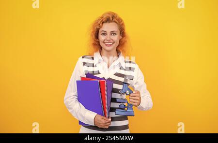 Professeur avec microscope sur jaune. Sciences biologiques pour la femme. La recherche microscopique. Une femme professeur de biologie scolaire tient un microscope. Femme enseignante de biol Banque D'Images