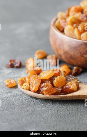 Raisins séchés dans un bol en bois ou une cuillère sur fond rustique, concept de fruits secs sains, raisins secs Banque D'Images