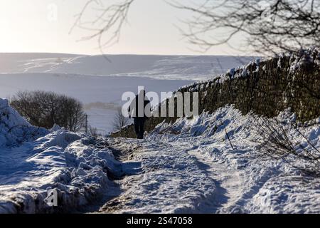 Un marcheur sur une voie enneigée près d'Oakworth, West Yorkshire Banque D'Images