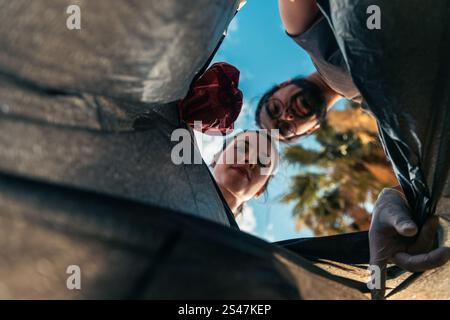 Un homme et une femme jettent des ordures dans un sac poubelle. Banque D'Images