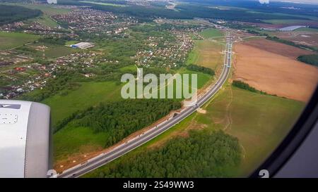 La vue de la fenêtre de l'avion de la ville, la route et la vue estivale du paysage, l'avion survole un quartier résidentiel, le concept de Banque D'Images