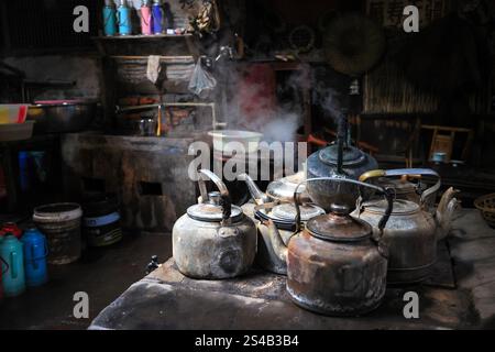 Bouilloires à thé sur le poêle à charbon avec éclairage latéral dans une ancienne maison de thé avec fond sombre dans le Sichuan, en Chine Banque D'Images