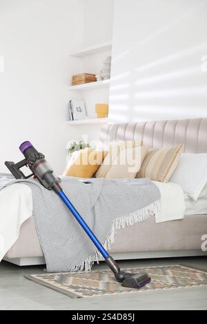 Un aspirateur sans fil reposant sur le lit à l'intérieur Banque D'Images
