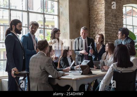Équipe d’affaires diversifiée collaborant sur un projet d’énergie durable utilisant des modèles d’éoliennes lors d’une réunion dans un bureau moderne. Inclusif et inoffensif Banque D'Images