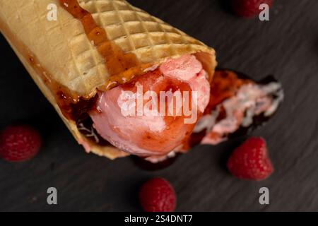 crème glacée à la framboise avec des baies de framboise rouges et de la confiture de baies fraîches sur une planche d'ardoise noire, crème glacée aromatisée aux baies avec des framboises fraîches et du noir Banque D'Images