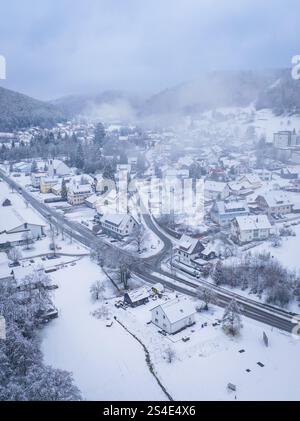 Petit village enneigé dans un paysage de montagne boisé, entouré de brume, Enzkloesterle, quartier Calw, Forêt Noire, Allemagne, Europe Banque D'Images