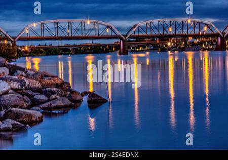 Un pont enjambe une rivière la nuit, avec les lumières se reflétant sur l'eau. La scène est sereine et paisible, avec le pont et l'eau créant un sens Banque D'Images