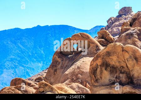 Une chaîne de montagnes avec une grande formation rocheuse qui ressemble à un cœur. Le ciel est bleu et les rochers bruns Banque D'Images