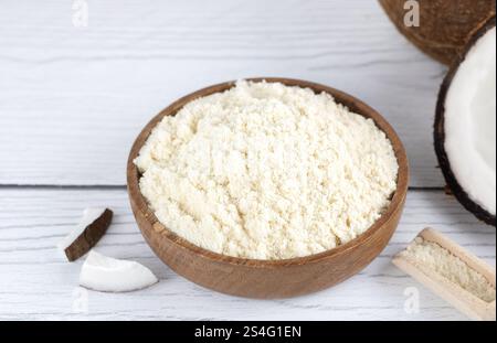 Farine de noix de coco dans un bol en bois et noix de coco fraîches sur un fond en bois. Ingrédients de cuisson. Nourriture sans gluten. Banque D'Images