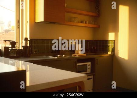 Istanbul, Turquie - 30 novembre 2024 : coucher de soleil chaud dans un coin cuisine moderne avec comptoir, évier, micro-ondes et cafetière dans un style minimaliste Banque D'Images