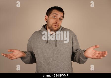 Les mains tendues vers l'extérieur, un homme haussa les épaules, paraissant confus. Les paumes ouvertes symbolisent son manque de compréhension de la situation. Son corps Banque D'Images