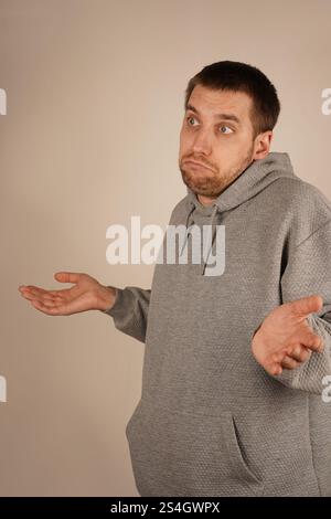Les mains tendues vers l'extérieur, un homme haussa les épaules, paraissant confus. Les paumes ouvertes symbolisent son manque de compréhension de la situation. Son corps Banque D'Images