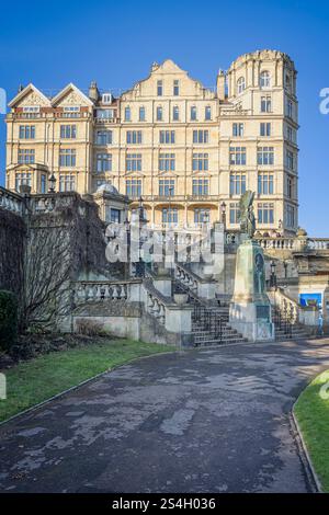 Statue commémorative du roi Édouard VII avec l'Empire Hotel derrière à la lumière du coucher du soleil dans Parade Gardens, Bath, Royaume-Uni le 11 janvier 2025 Banque D'Images