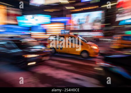 Un taxi jaune passant par Times Square, New York, Manhattan, Motion floue la nuit, Banque D'Images