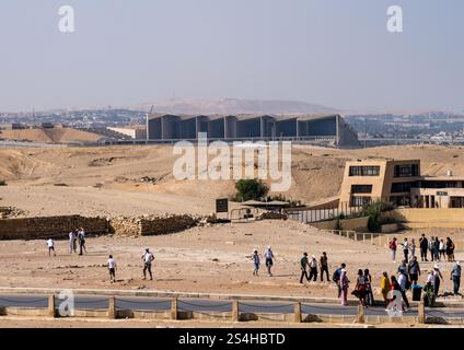 Gizeh, Egypte - 30 octobre 2024 : les touristes approchent de la Grande Pyramide avec le nouveau Grand Musée égyptien moderne en arrière-plan Banque D'Images