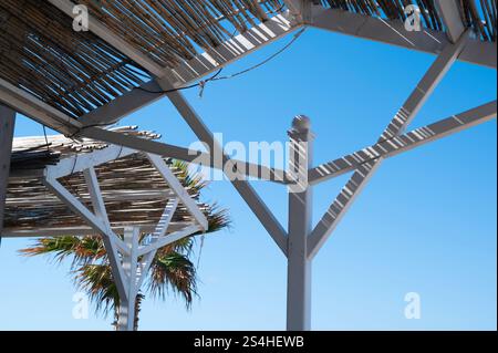 Bar de plage toit de chaume avec ombre de palmiers et soleil bleu ciel sur la plage de la mer. Banque D'Images