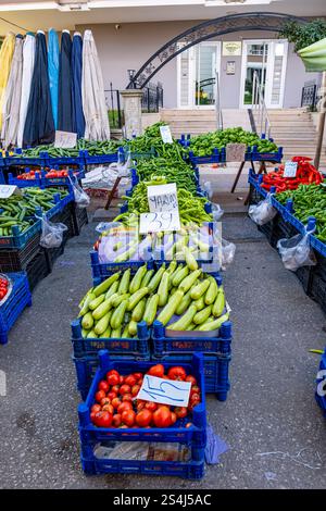 Un marché avec une variété de légumes et de fruits. Les légumes sont présentés dans des caisses bleues. Le marché est en plein air et a une atmosphère ensoleillée Banque D'Images