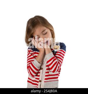 Portrait d'une fille mignonne et fatiguée alors qu'elle bâille avant le coucher. Photographié sur un fond blanc. Banque D'Images