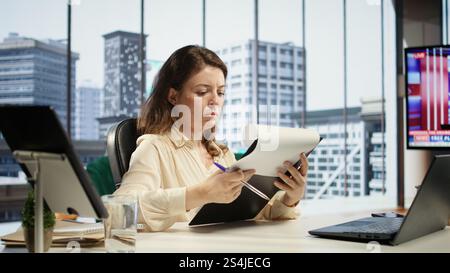 Le chef de l'entreprise signe des contrats de travail et des ententes pour approuver les demandes de congé et d'autres documents à des fins de productivité. PDG femme d'affaires travaillant sur la gestion juridique, success story. Caméra B. Banque D'Images