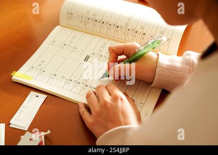 Gros plan des mains d'une jeune femme étrangère alors qu'elle écrit des kanji pour apprendre le japonais Banque D'Images
