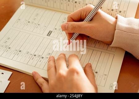Gros plan des mains d'une jeune femme étrangère alors qu'elle écrit des kanji pour apprendre le japonais Banque D'Images