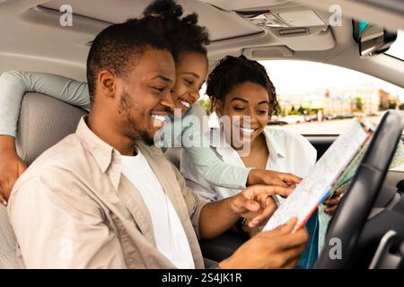 Bonne famille africaine tenant la carte assis dans la voiture choisir la destination Banque D'Images