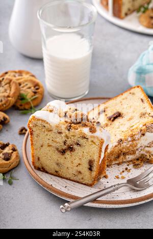 Gâteau bundt appétissant avec glaçage et biscuits écrasés, servi avec du lait sur une surface en pierre Banque D'Images