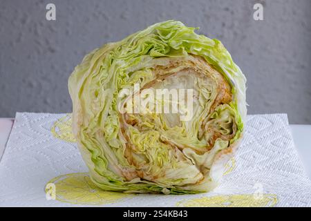 Vue latérale intérieure d'une tête de laitue iceberg nouvellement achetée qui devient brune après avoir été coupée. Banque D'Images