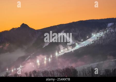 Une vue sereine et pittoresque au crépuscule mettant en valeur les pistes de ski illuminées magnifiquement nichées dans un paysage de montagne enneigé Banque D'Images