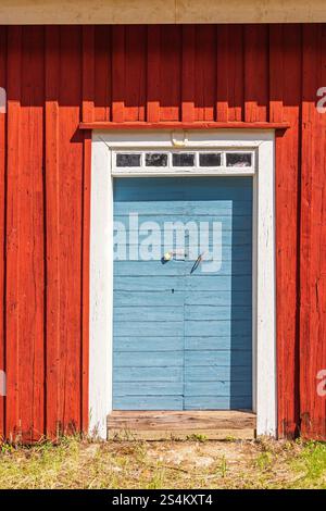 Porte en bois bleu sur un chalet en bois rouge Banque D'Images