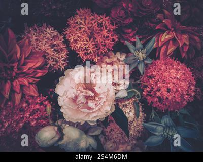 Une image de style vintage mettant en vedette un riche arrangement de fleurs artificielles dans des rouges et roses profonds, rappelant une célébration du nouvel an chinois. Banque D'Images