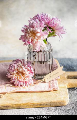 Les chrysanthèmes élégants dans un vase en verre texturé, fixés sur une planche de bois, créent un thème automnal Une étiquette automne manuscrite ajoute une touche charmante à cela Banque D'Images