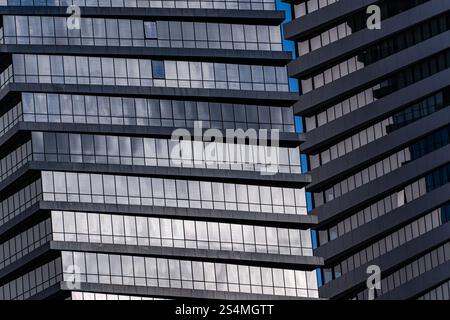 Un regard détaillé sur un gratte-ciel moderne avec des motifs géométriques formés par des fenêtres et des reflets. L'image capture la conception complexe et réf Banque D'Images