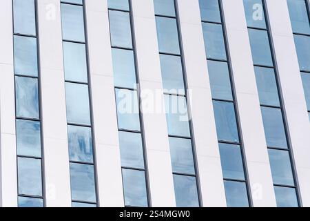 Une vue détaillée d'un bâtiment moderne avec un motif rythmé de panneaux verticaux blancs et en verre qui illustrent le style architectural contemporain A. Banque D'Images