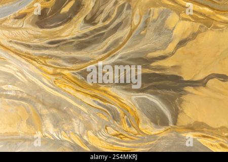 Cette image présente une texture abstraite captivante avec des motifs fluides ressemblant à une surface en marbre dans des tons dorés et beiges idéales pour les arrière-plans o Banque D'Images