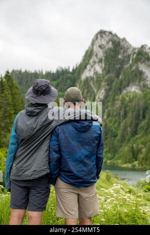 Deux personnes embrassent tout en admirant le paysage montagneux pittoresque du lac de Taney, la Suisse verdure luxuriante et l'eau sereine créent un guichet automatique tranquille Banque D'Images