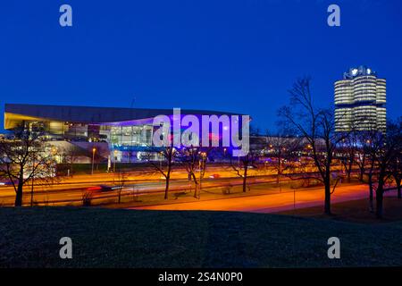 Moderne Architektur BEI Nacht. Die BMW-Welt und der BMW-Turm am Abend. Ausstellungsstätte und Hauptverwaltung des Fahrzeugherstellers BMW in München. München Bayern Deutschland *** architecture moderne la nuit BMW Welt et la tour BMW la nuit Centre d'exposition et siège du constructeur automobile BMW à Munich Munich Bavière Allemagne Copyright : xRolfxPossx Banque D'Images