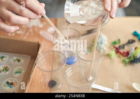 Artisanat avec de la résine : mains versant du liquide dans des moules pour des bijoux de bricolage et des projets d'art. Banque D'Images