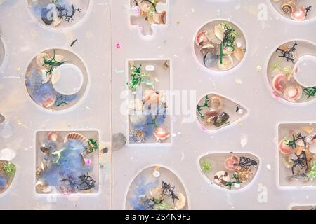 Art créatif en résine avec des coquilles colorées et des éléments décoratifs en formes de moule. Banque D'Images