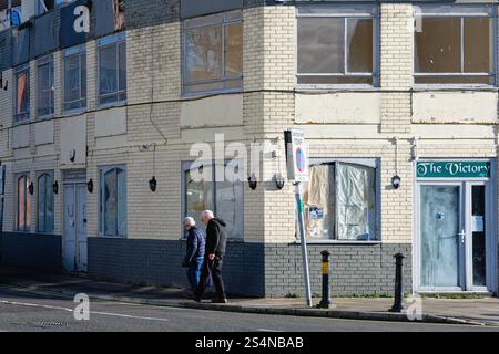 Un couple âgé passant devant le Victory Pub fermé sur le Hard à Portsmouth Hampshire Angleterre Banque D'Images