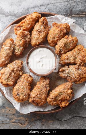 Ailes de poulet croustillantes Bburinkle avec un gros plan de fromage, d'oignon et d'ail sur l'assiette sur la table. Vue de dessus verticale Banque D'Images