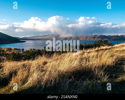 Belle vue d'automne avec vent soufflé au lac Sevan, paysage sur la colline près du monastère Sevanavank, beaucoup de montagne sur le ciel bleu et blanc pelucheux CLO Banque D'Images