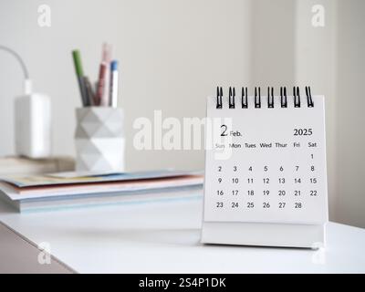 Un bureau de calendrier de février 2025 pour l'organisateur de planifier et rappeler debout sur le bureau blanc dans la salle de travail à la maison. Calendrier de petite table blanc avec t Banque D'Images