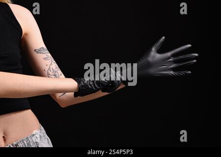 Tatoueur professionnel portant des gants sur fond noir, gros plan Banque D'Images