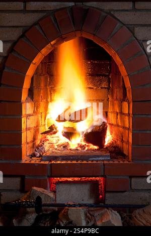 Poker, bois de chauffage et les flammes du feu dans la cheminée dans la soirée Banque D'Images