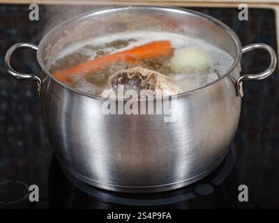 Mijoter le bouillon de poulet en pot d'acier sur une plaque de cuisson close up Banque D'Images