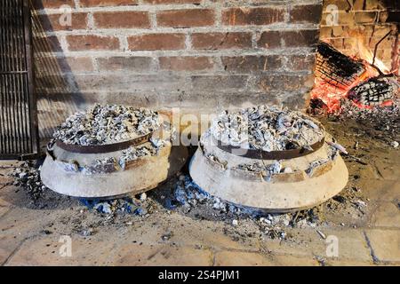 Cuisson du péka traditionnel dalmate dans des pots en métal sous des charbons brûlants Banque D'Images